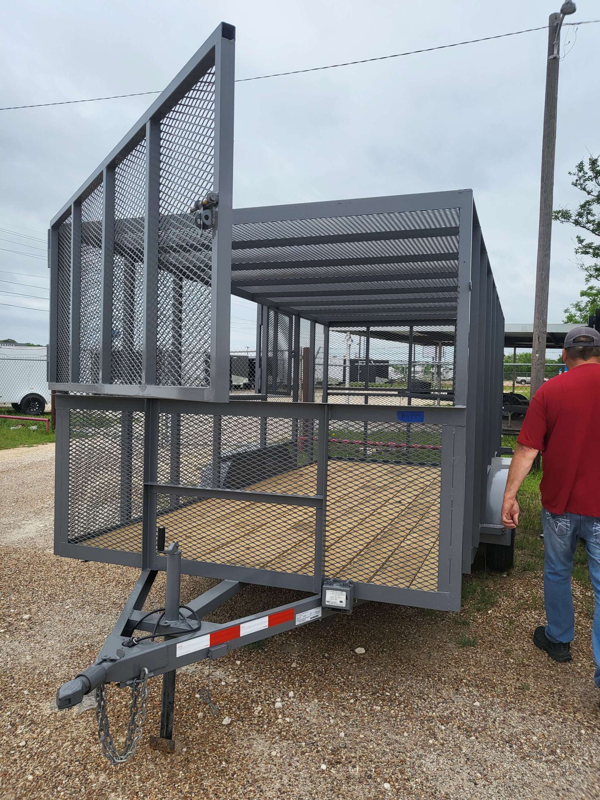 A man in a red shirt is standing next to a trailer.