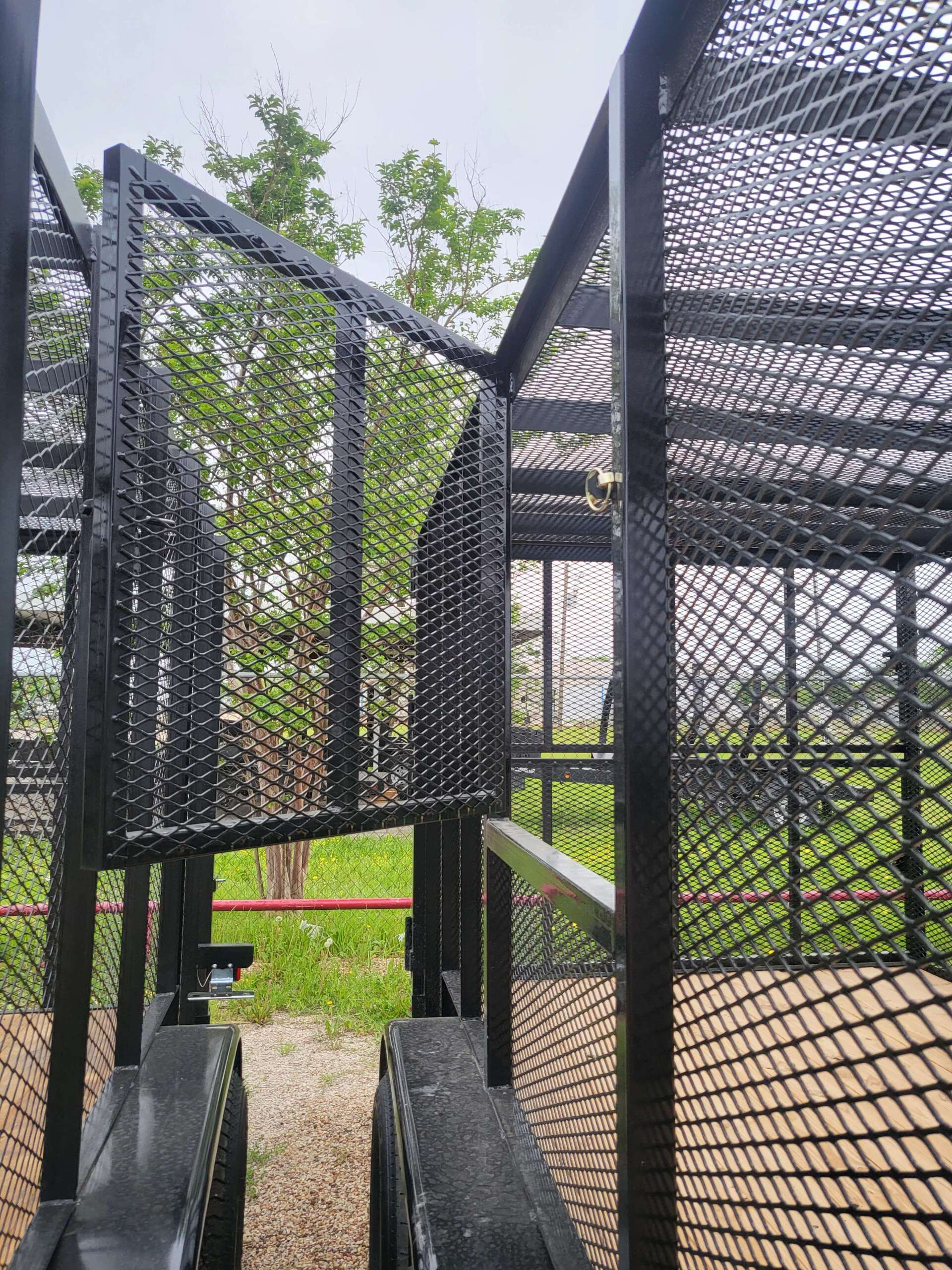 A close up of a metal structure in a park with trees in the background.