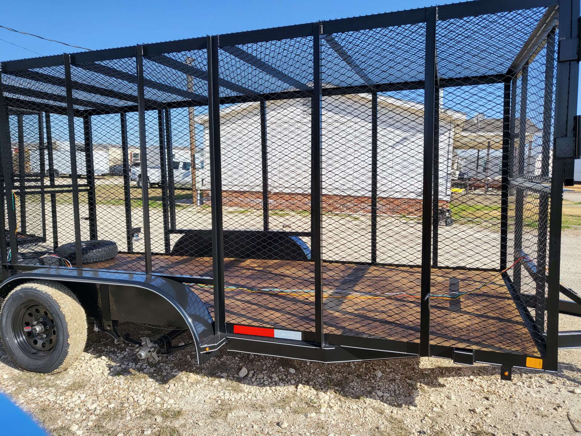 A trailer with a cage on top of it is parked in a dirt field.