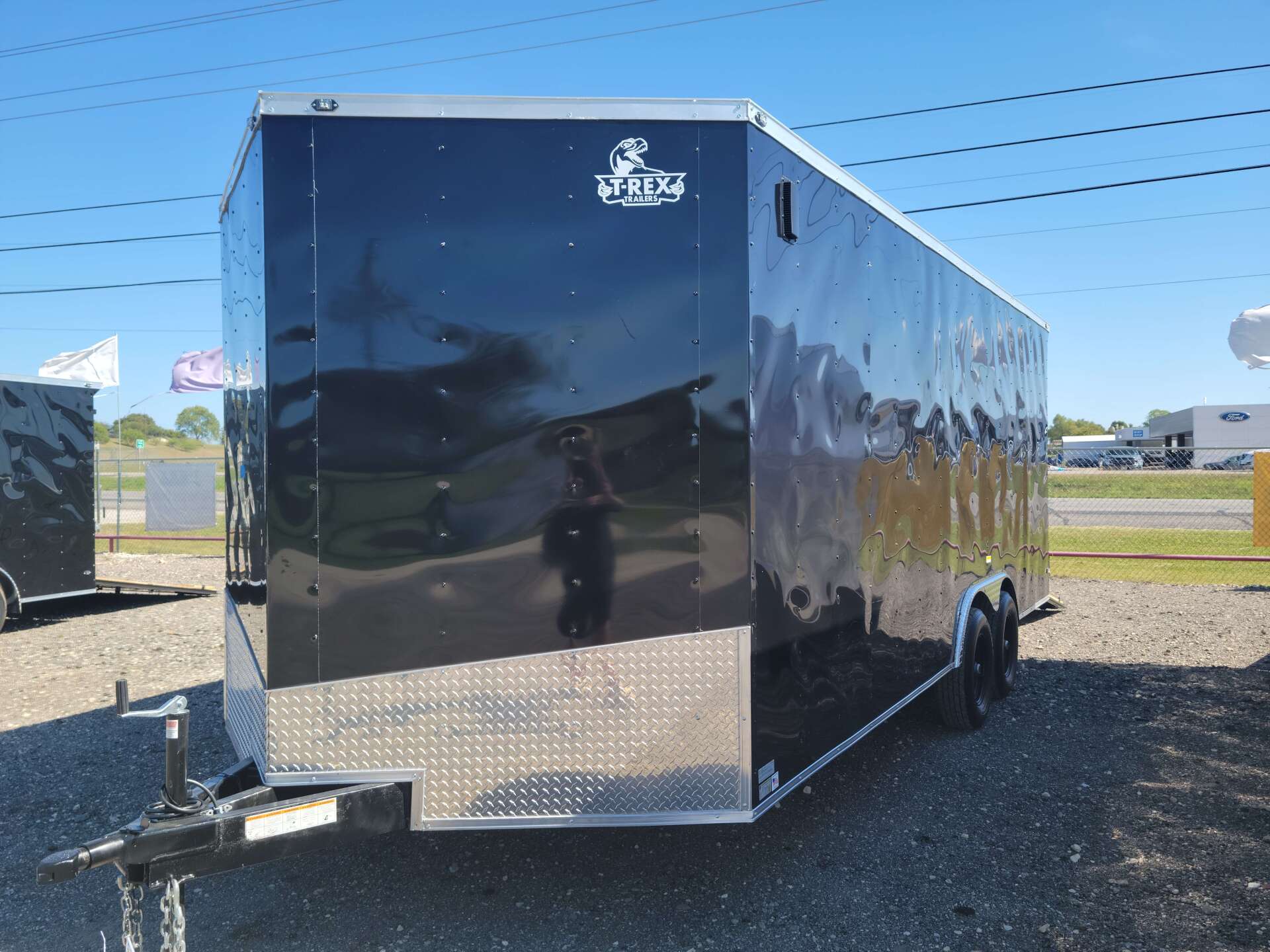 A black and silver trailer is parked on the side of the road.