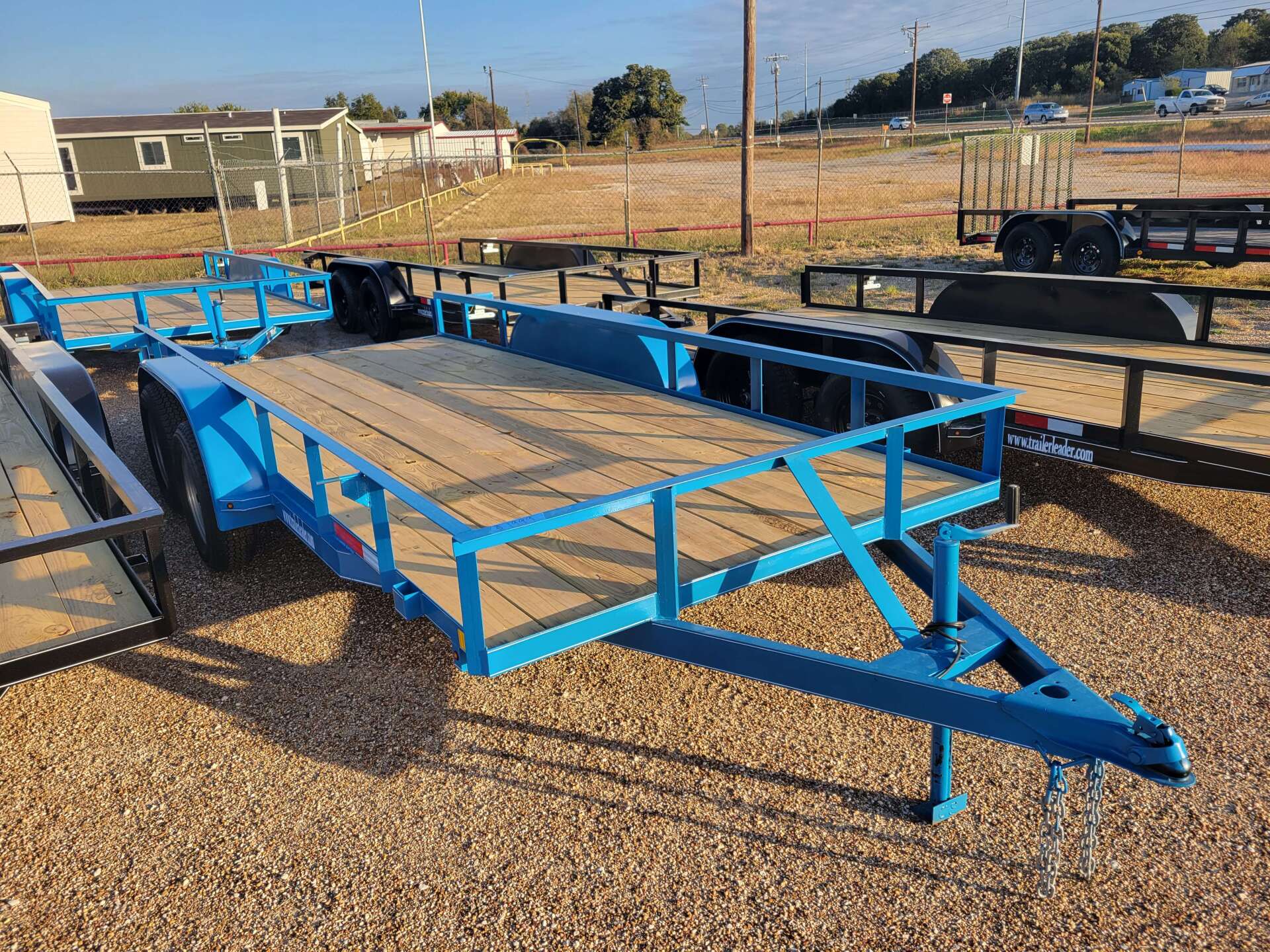 A blue trailer is sitting on top of a gravel lot.