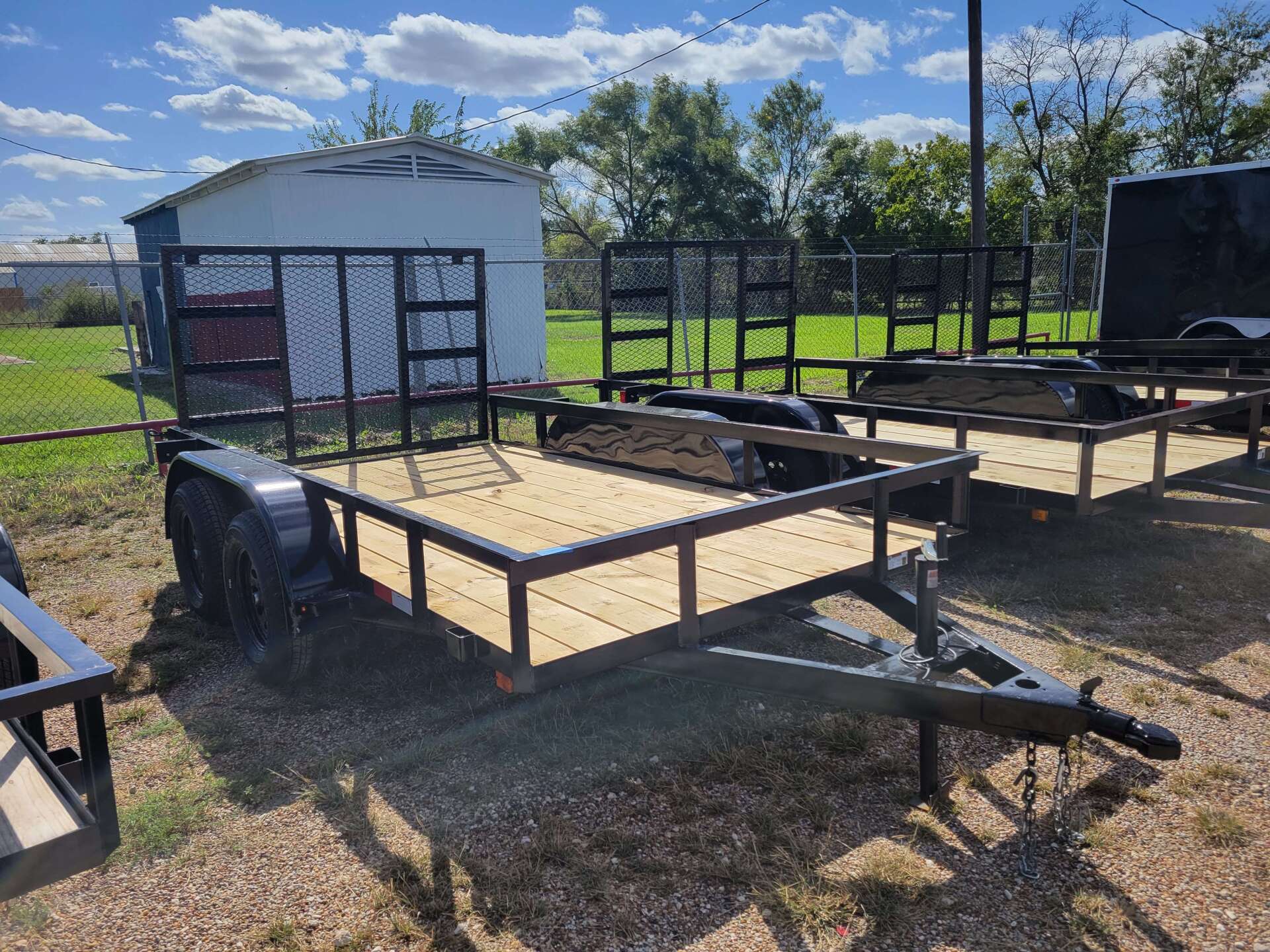 A trailer is sitting on top of a dirt field next to a fence.