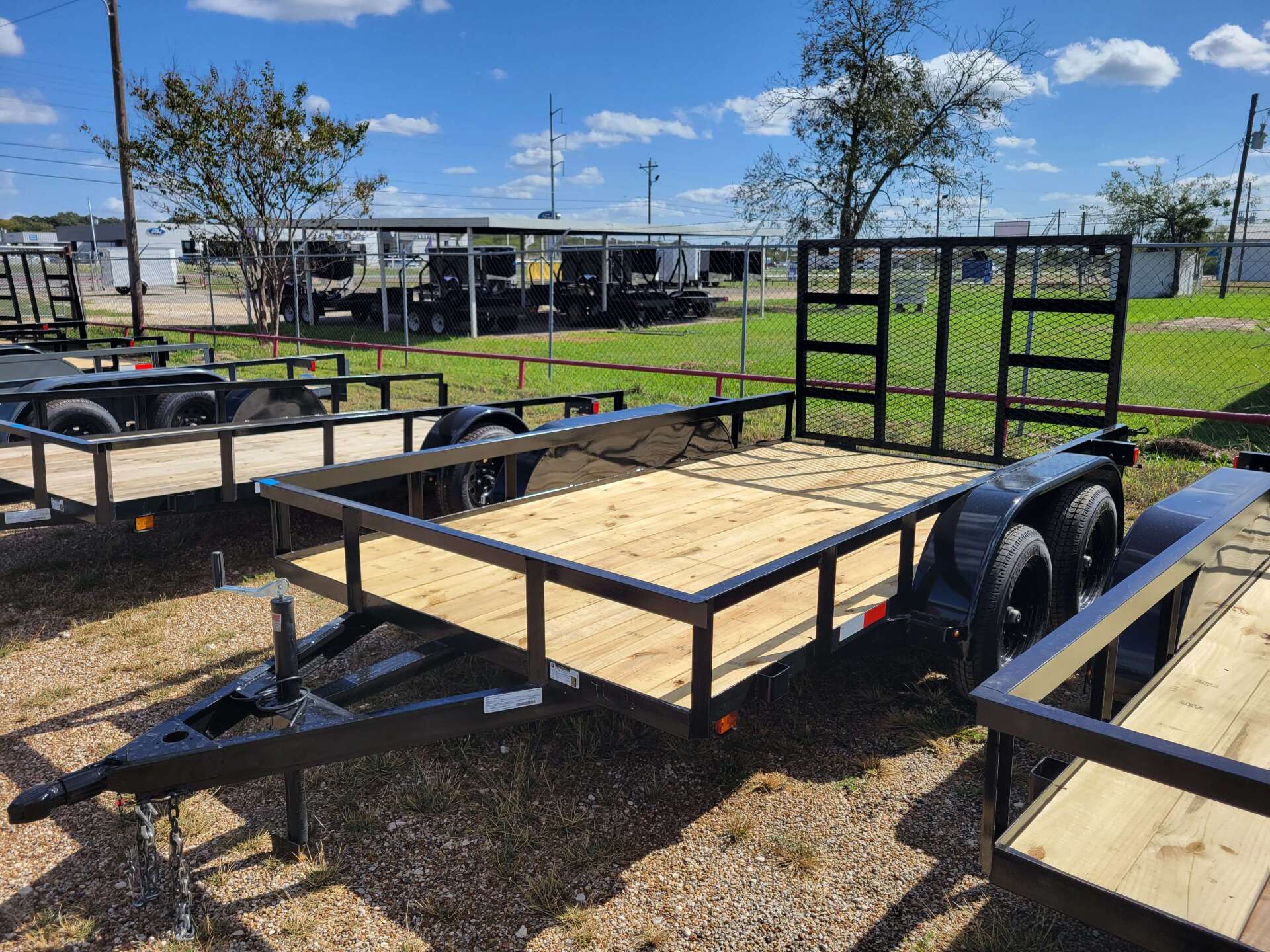 A trailer with a wooden deck is sitting on top of a dirt field.