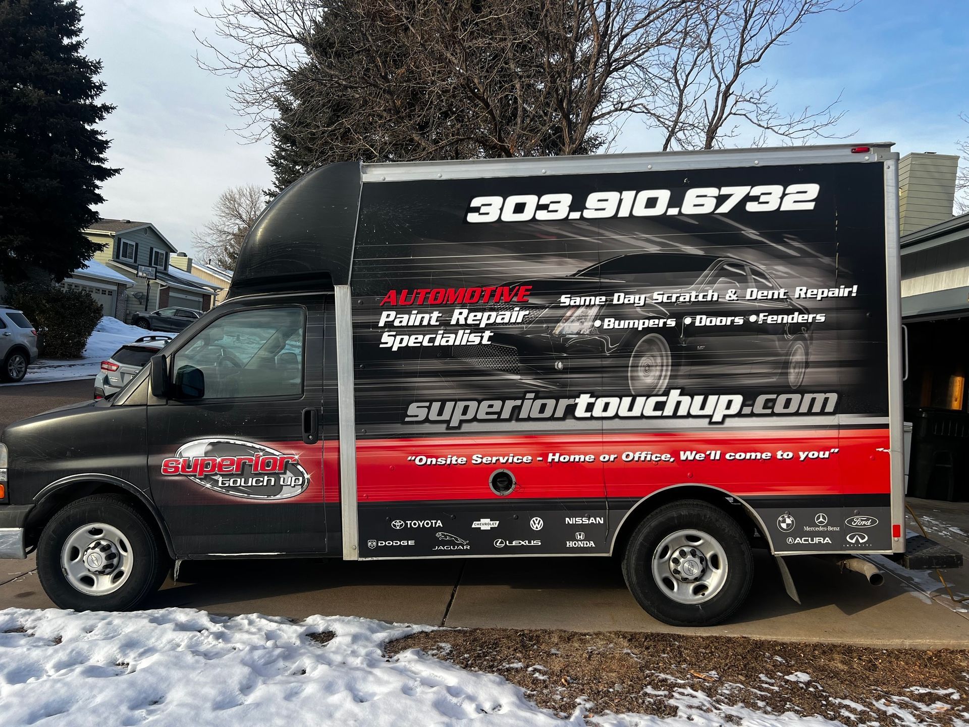 A black and red van with the website superiortouchup.com on the side is parked in the snow.