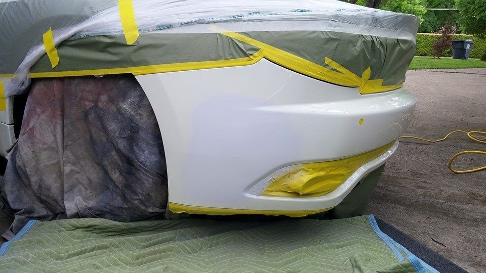 A white car with yellow tape on it is being painted