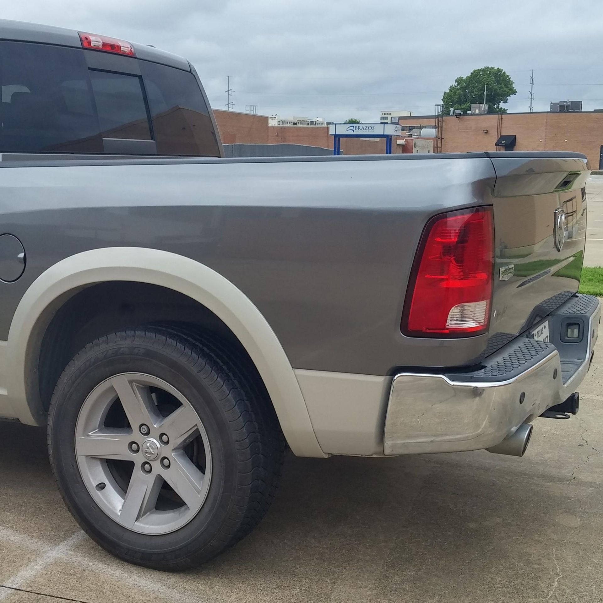 A gray truck with a red tail light is parked in a parking lot