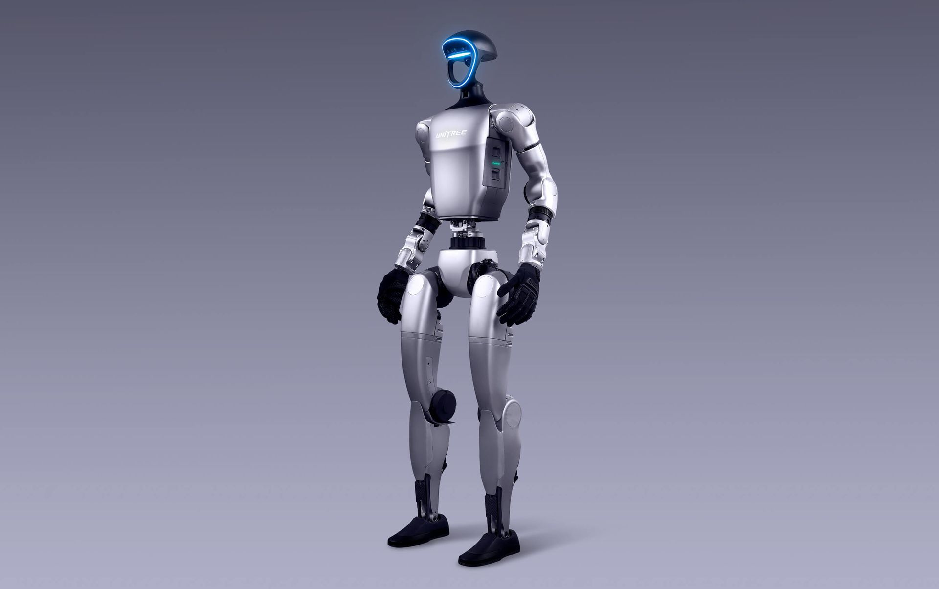 Robot with silver body and blue head lighting standing against a gray backdrop.