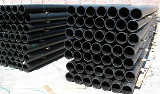 Pilas de tubos de plástico negro, probablemente para construcción o plomería.