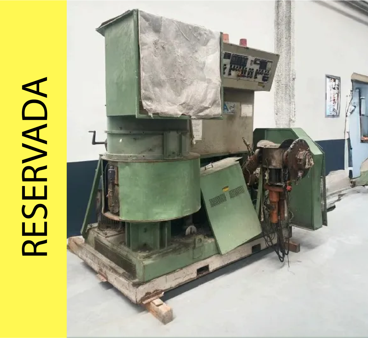 Maquina industrial verde sobre palet de madera, con cuadro de mandos y revestimientos.