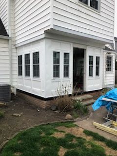 A deck with a white railing and a ladder in front of a house.
