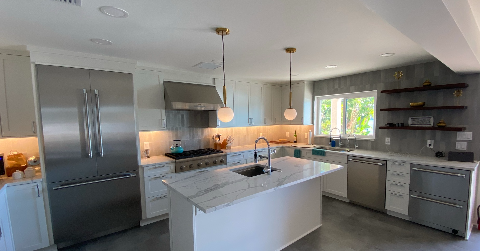 A kitchen with white cabinets , stainless steel appliances , and a large island.