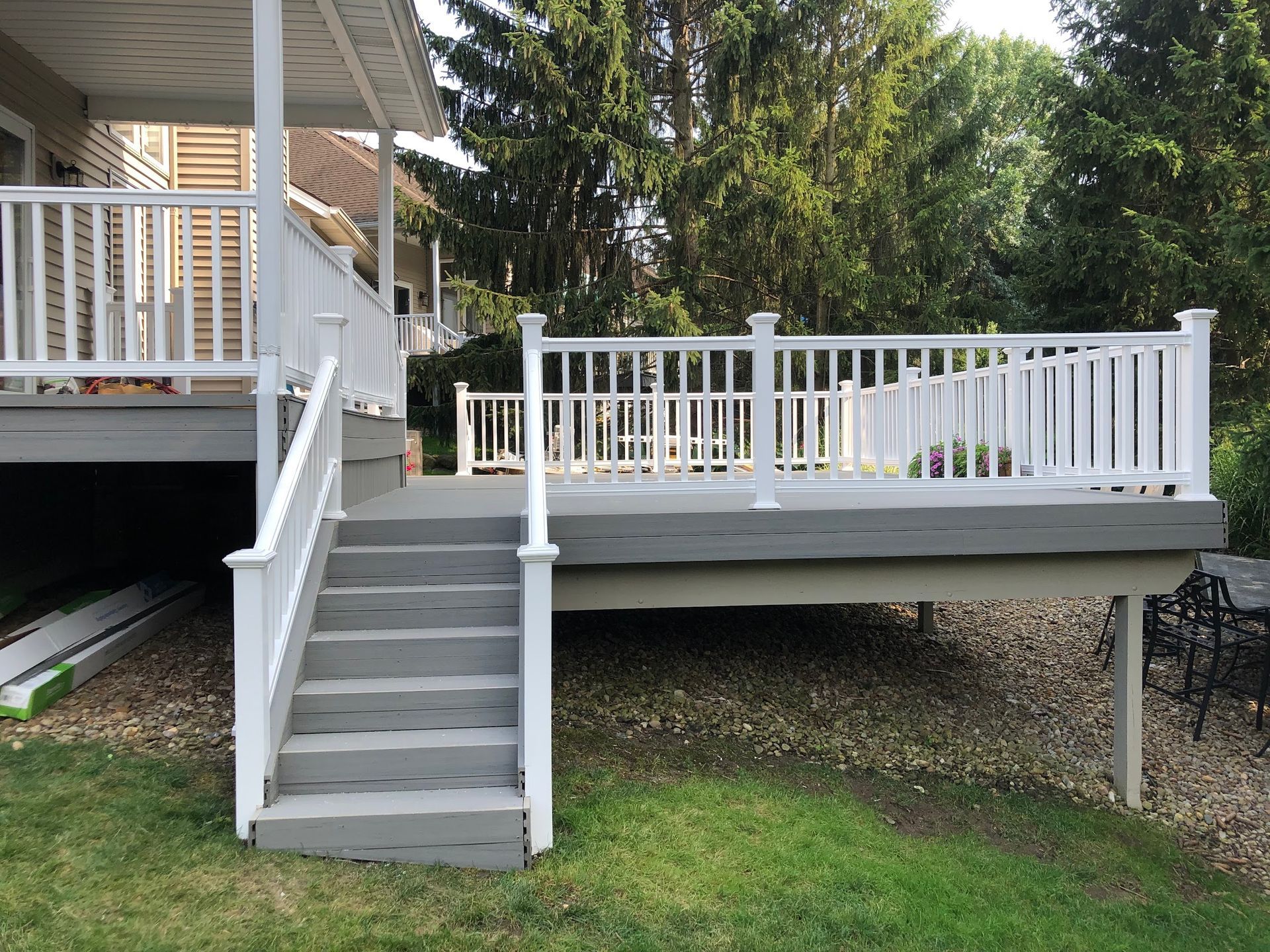 A large deck with stairs leading up to it and a white railing.