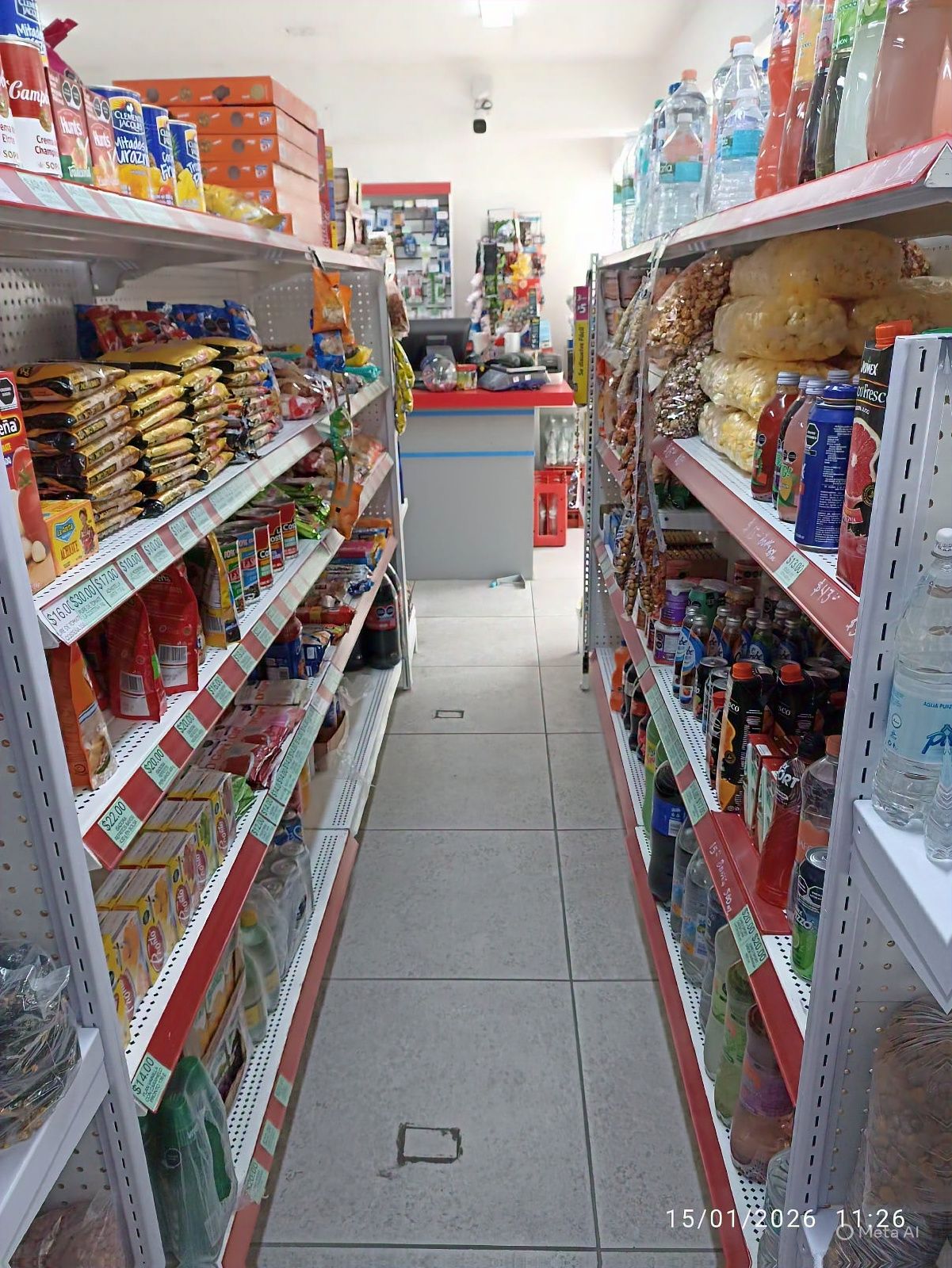 Filas de estantes repletos de alimentos envasados ​​en una pequeña tienda, con un borde rojo.