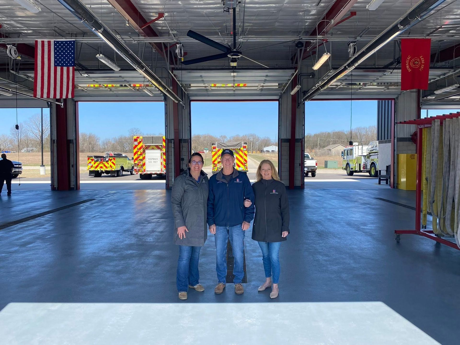 TBG leaders at a completed fire station bay with engines in the background