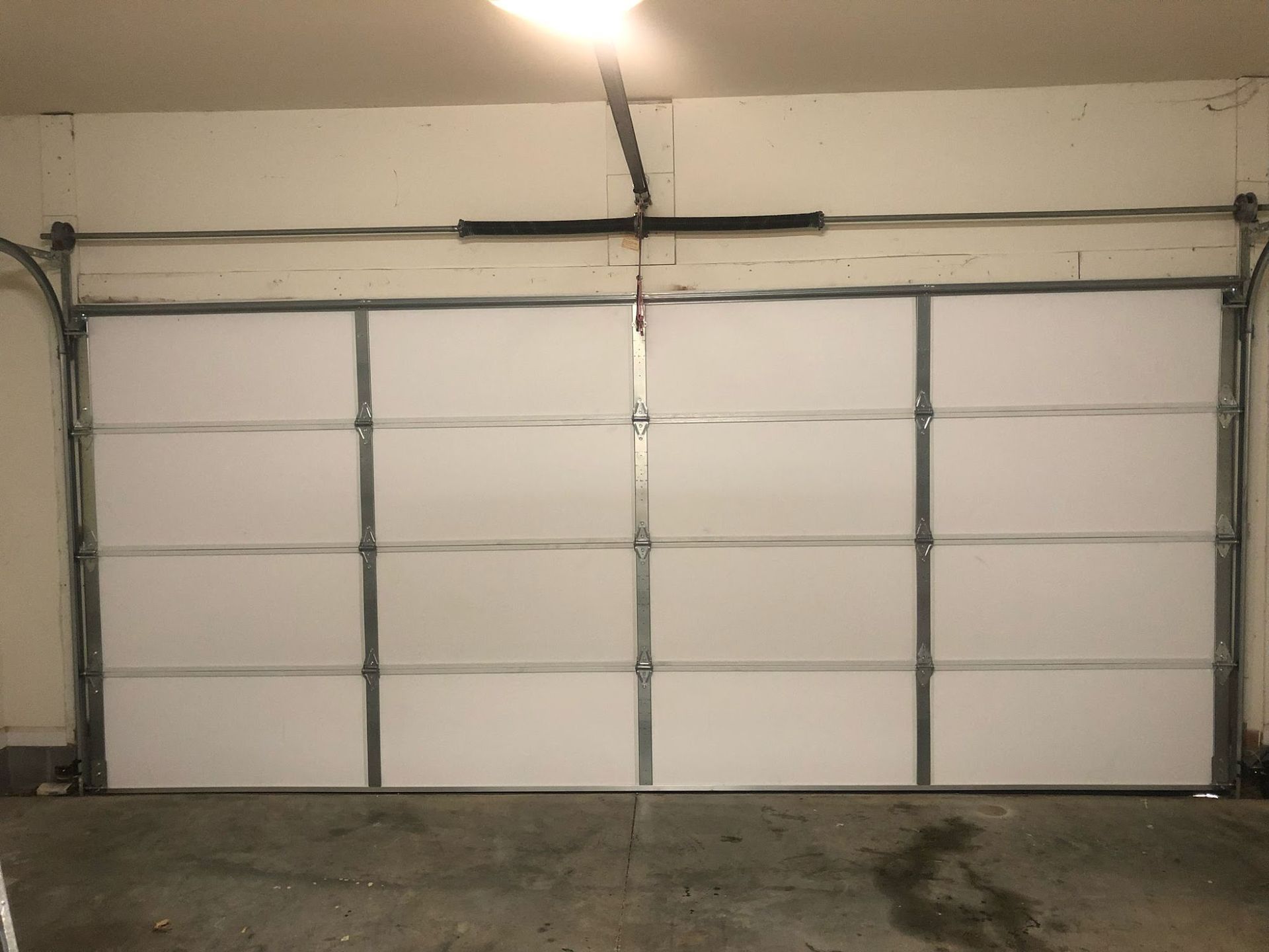 White garage door with metal framing, closed, in a garage setting.