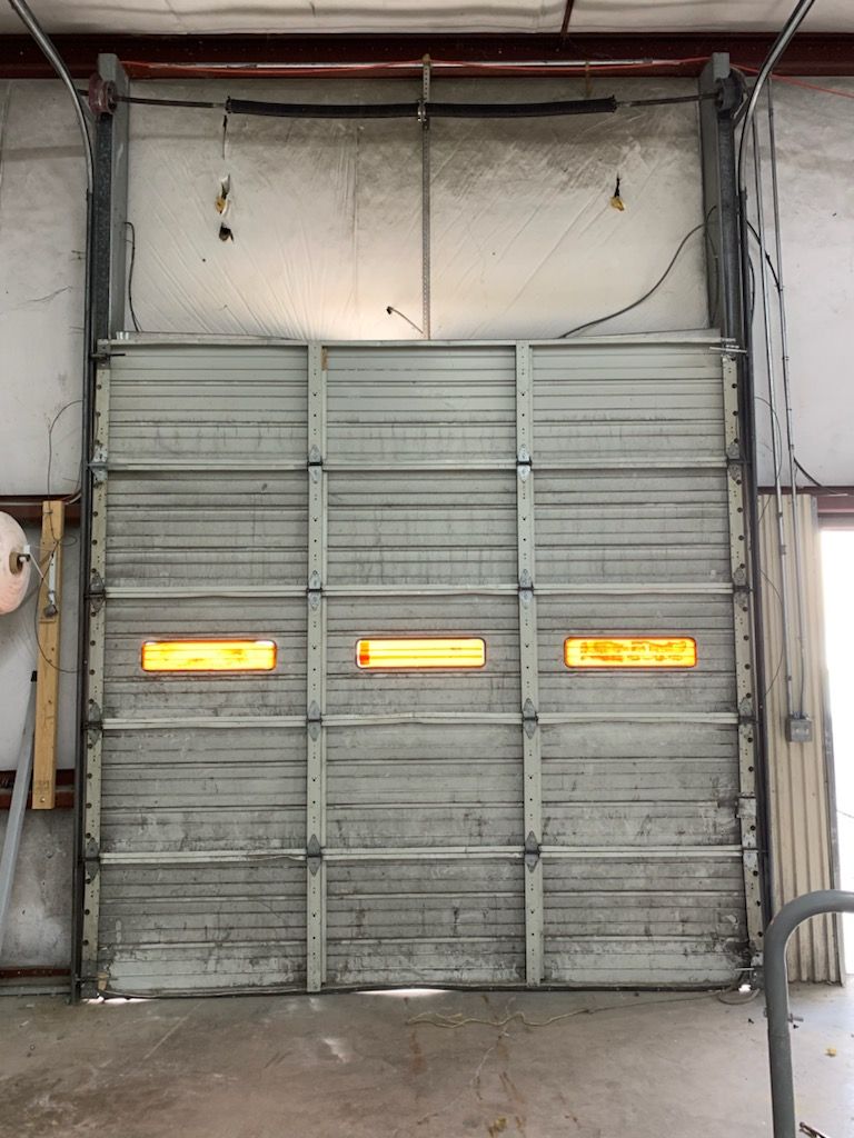 A closed, industrial-style garage door with three windows lit from within.