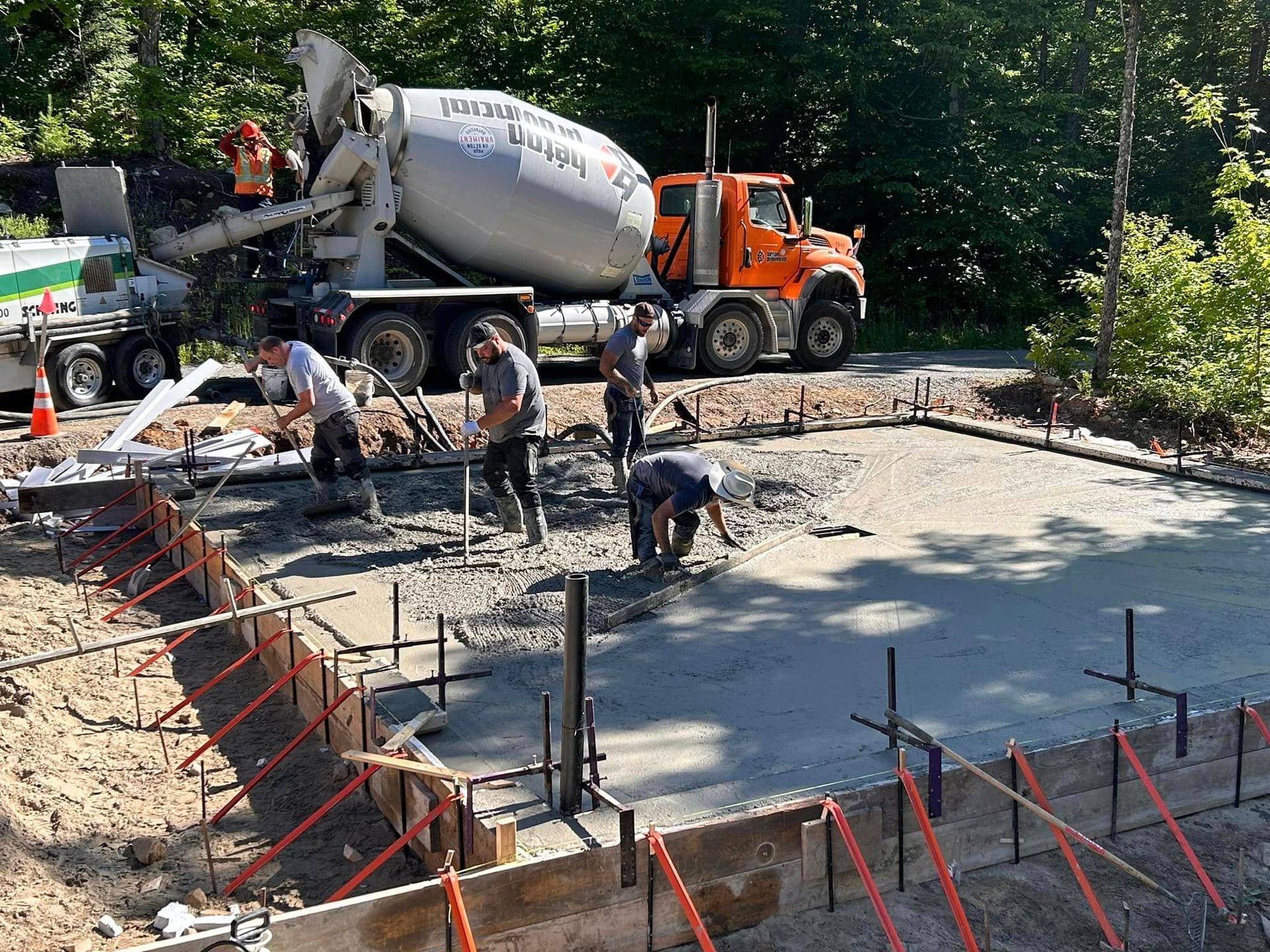 Un camion malaxeur à béton verse du béton sur un chantier de construction.