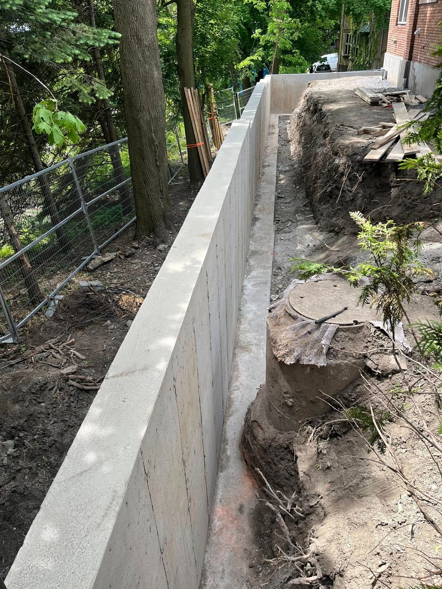 Un mur de béton est en cours de construction au sommet d'une colline de terre.