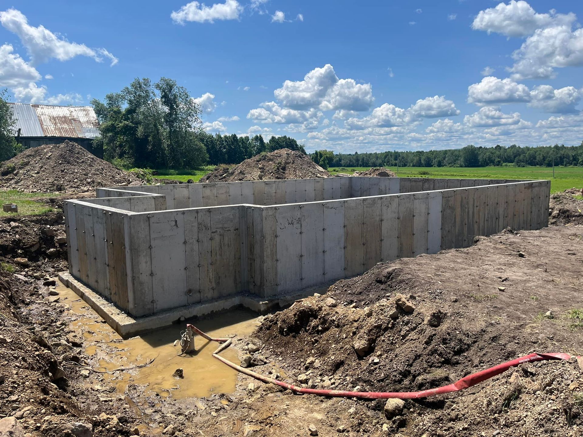 Une grande fondation en béton est en cours de construction dans un champ de terre.