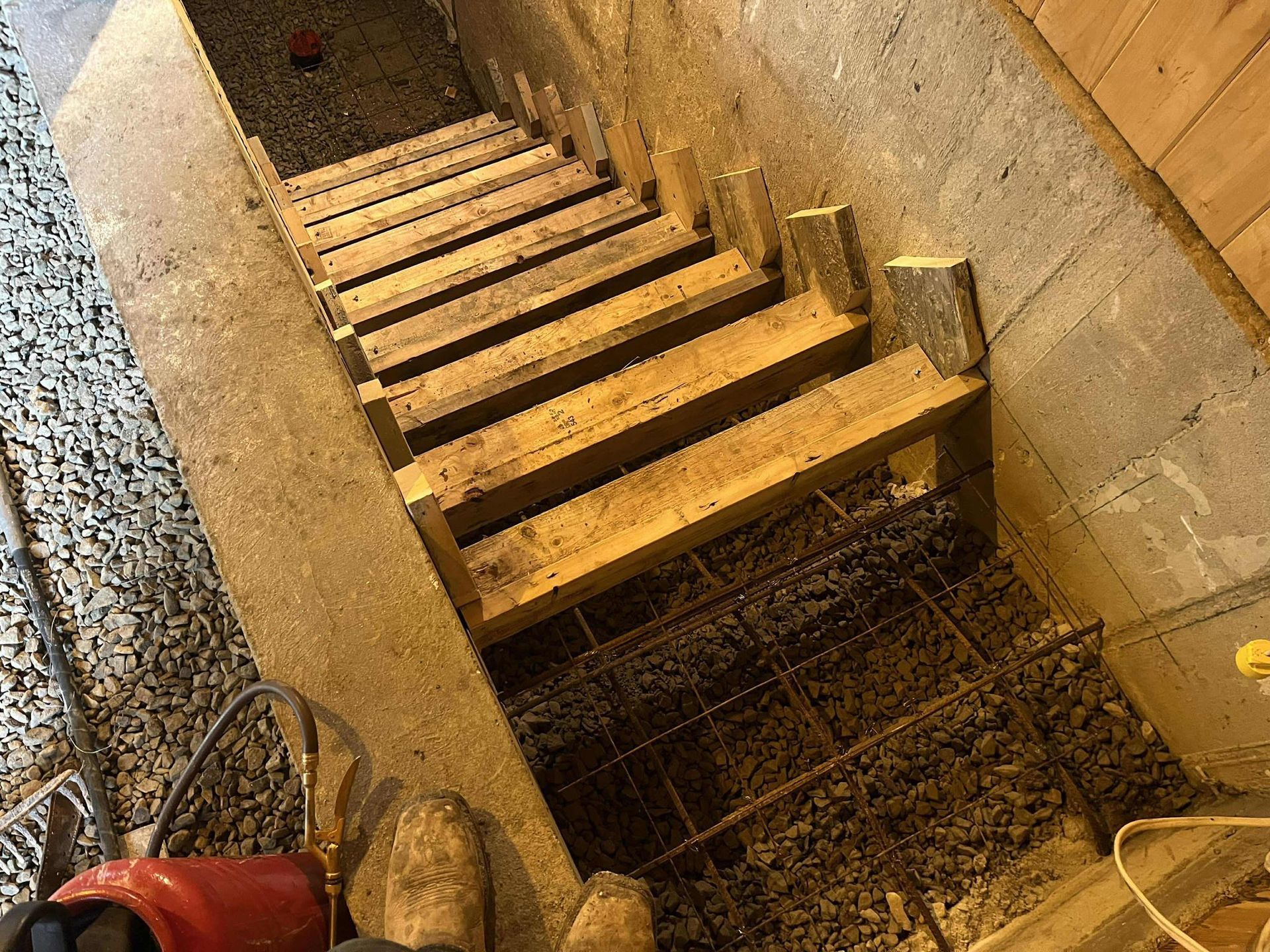 Un escalier en bois est en cours de construction dans un sous-sol.