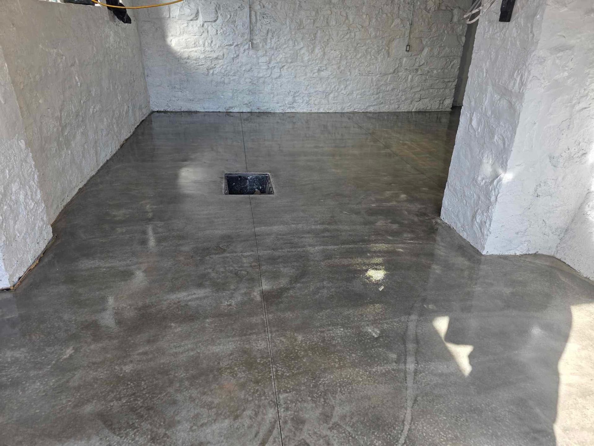 Un sol en béton dans une pièce avec des murs blancs et un trou dans le sol.