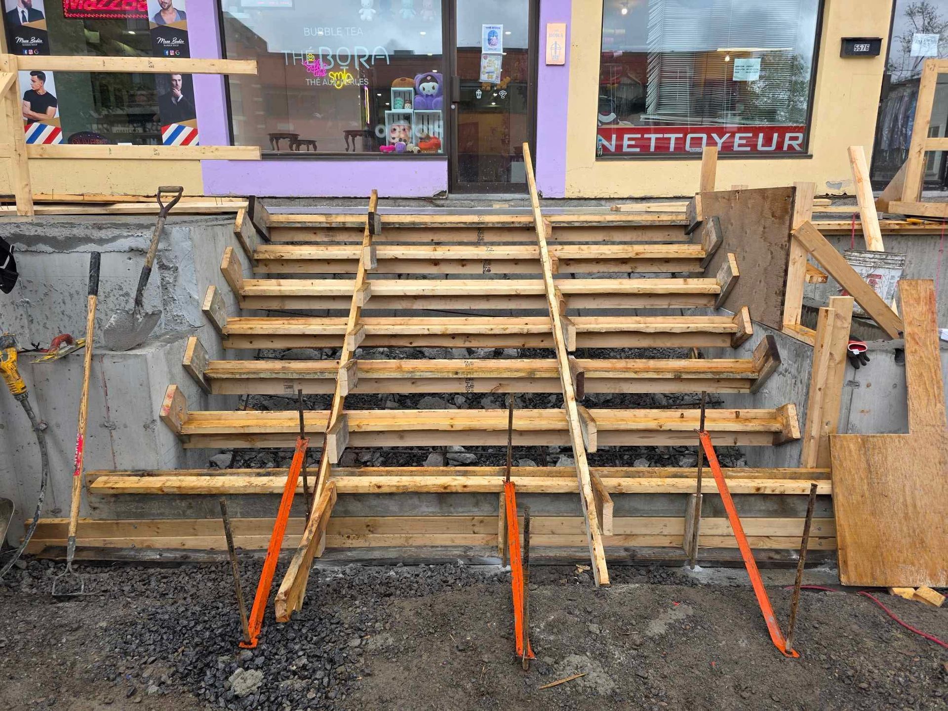 Un escalier en bois est en cours de construction devant un salon de coiffure.