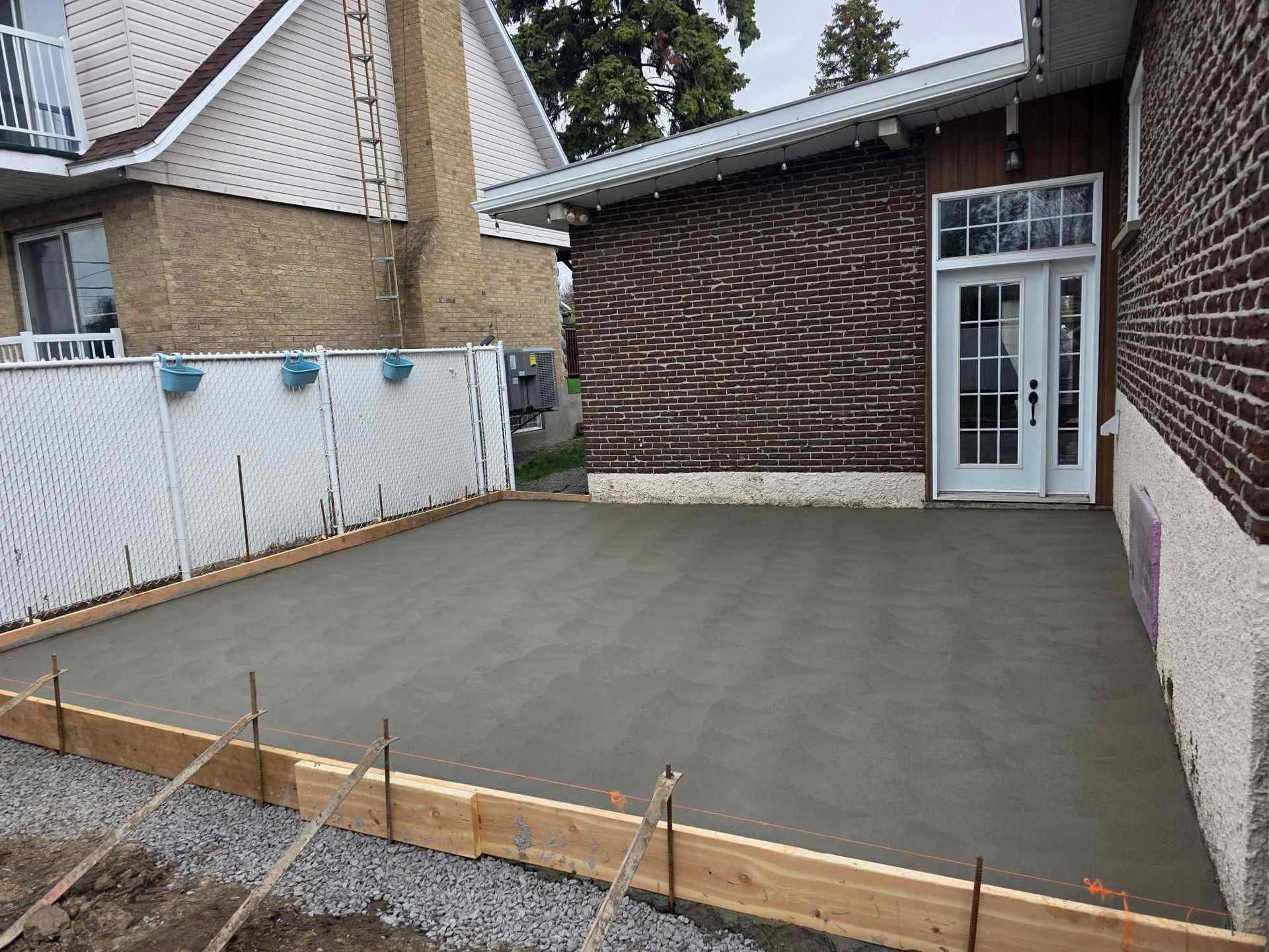 Une allée en béton est en cours de construction devant une maison en briques.