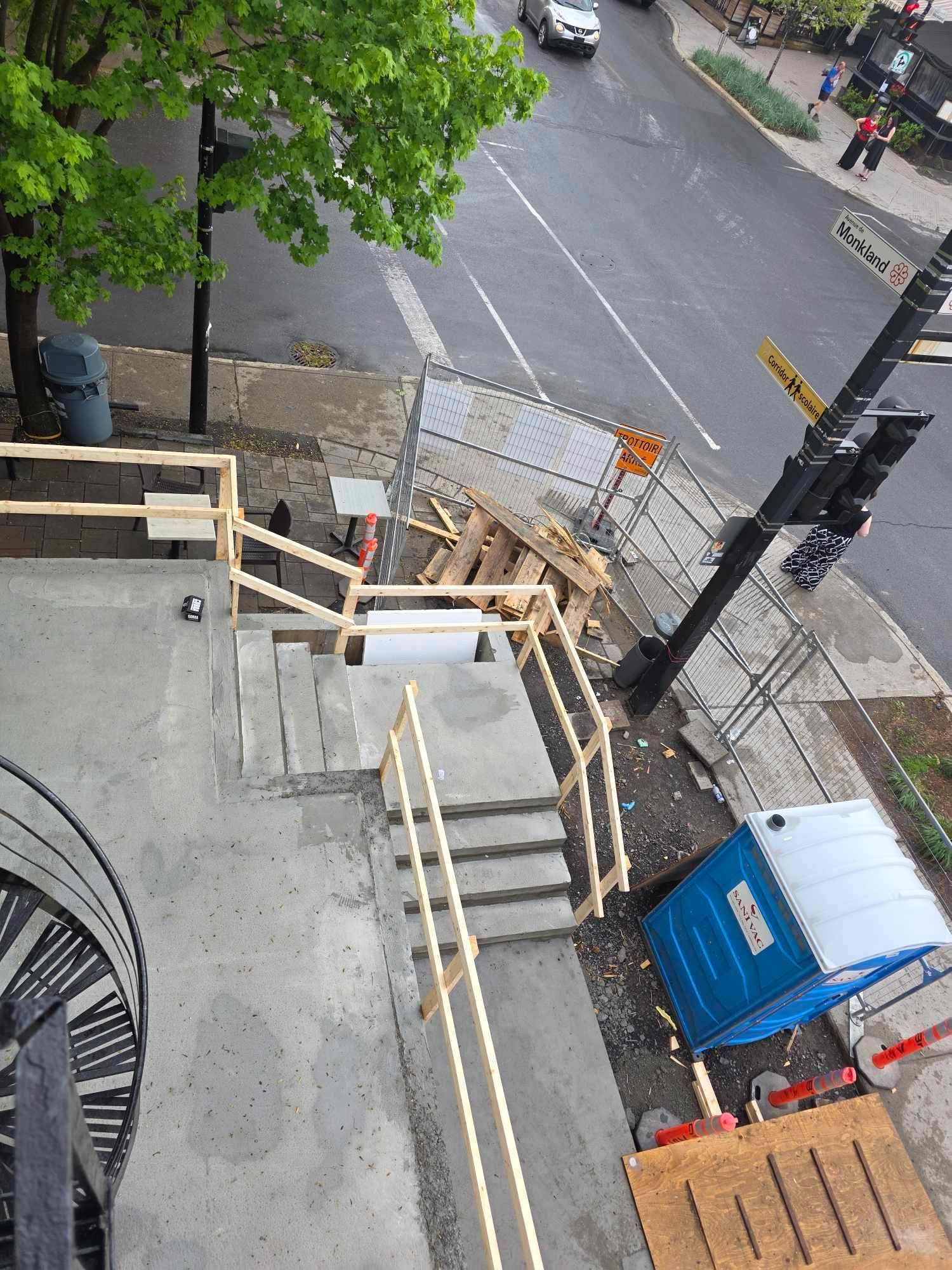 Une vue aérienne d'un chantier de construction avec des escaliers et des toilettes portables bleues