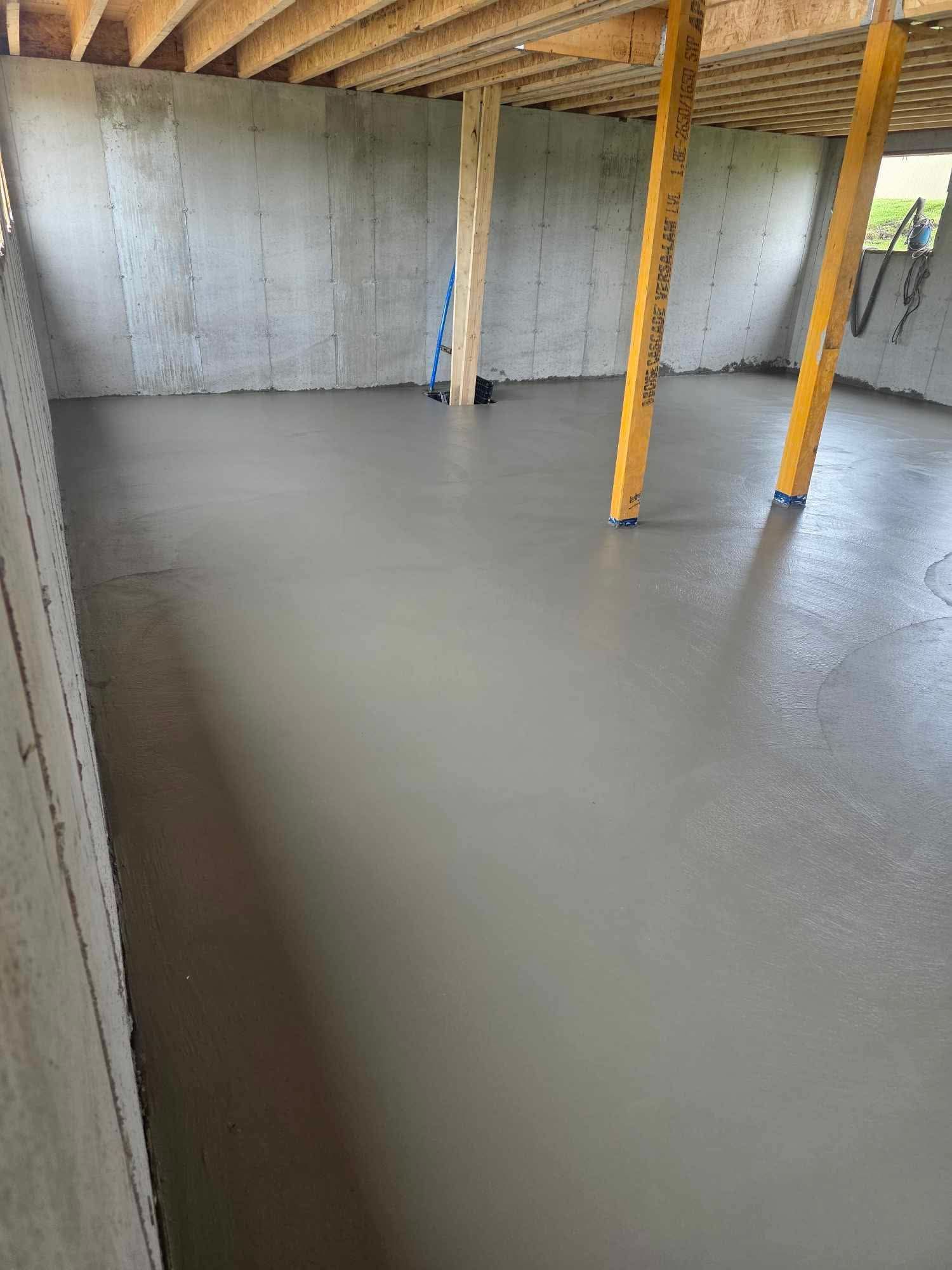 Un plancher en béton dans un sous-sol en construction avec des poutres en bois.