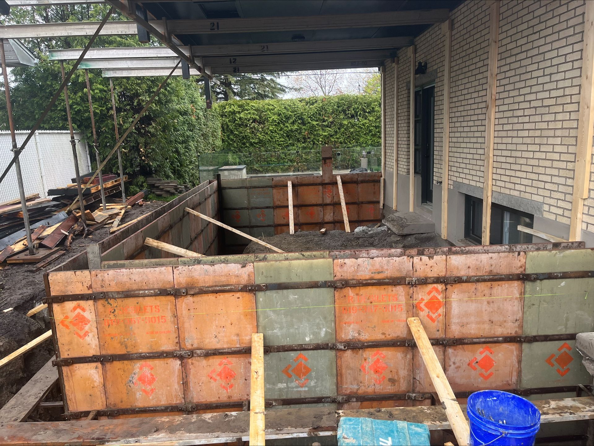 Un mur de béton est en cours de construction devant un bâtiment en briques.