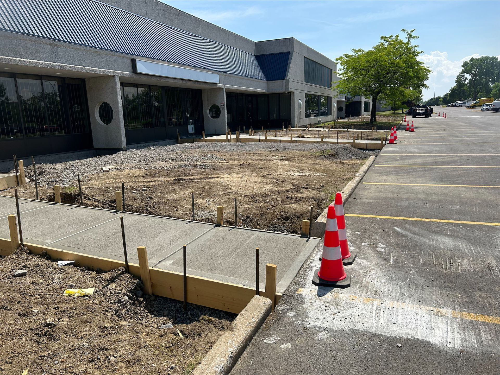 Une passerelle en béton est en cours de construction devant un grand bâtiment.