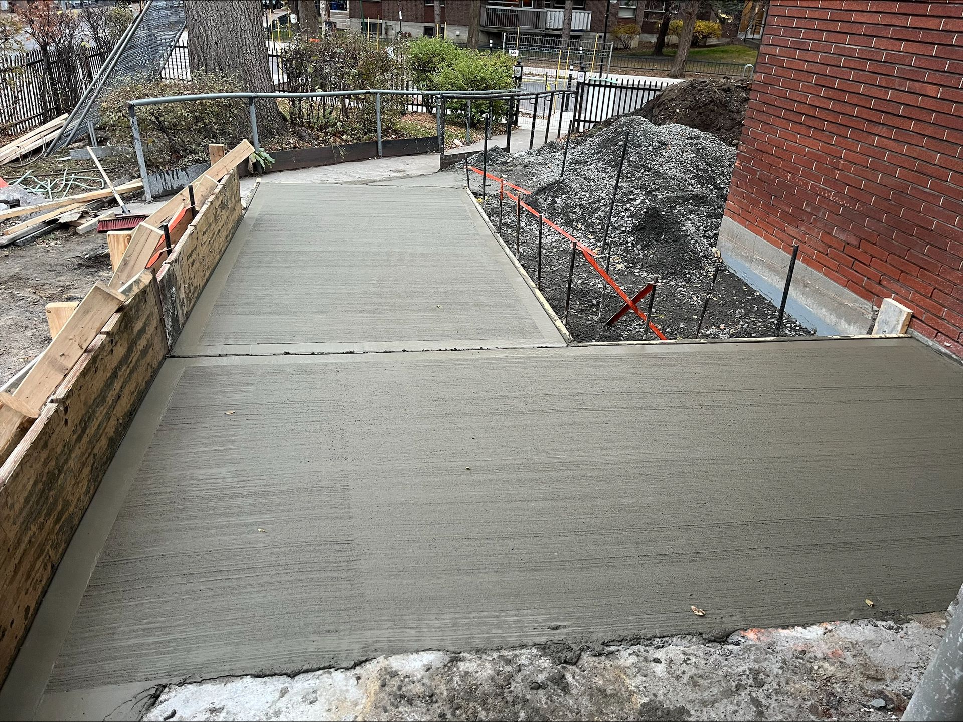 Une rampe en béton est en cours de construction à côté d'un bâtiment en briques.