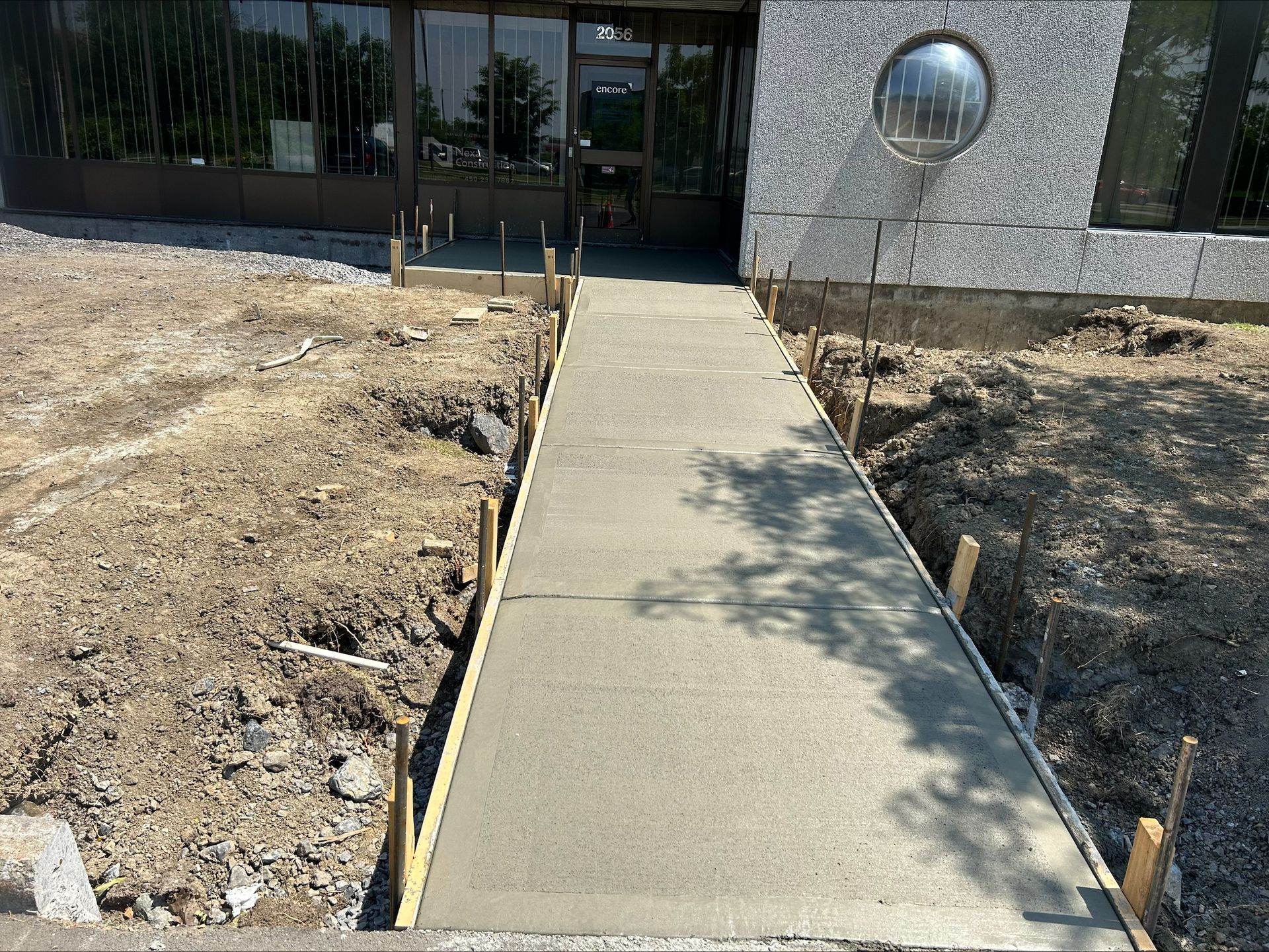 Une passerelle en béton est en cours de construction devant un bâtiment.