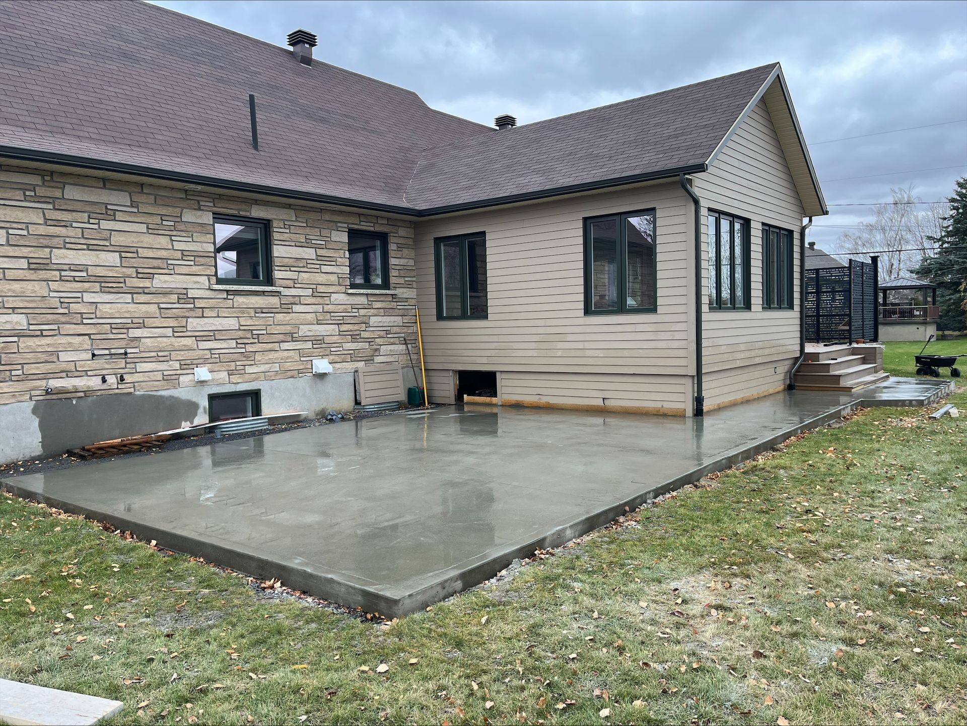 Une maison en briques avec un patio en béton devant.