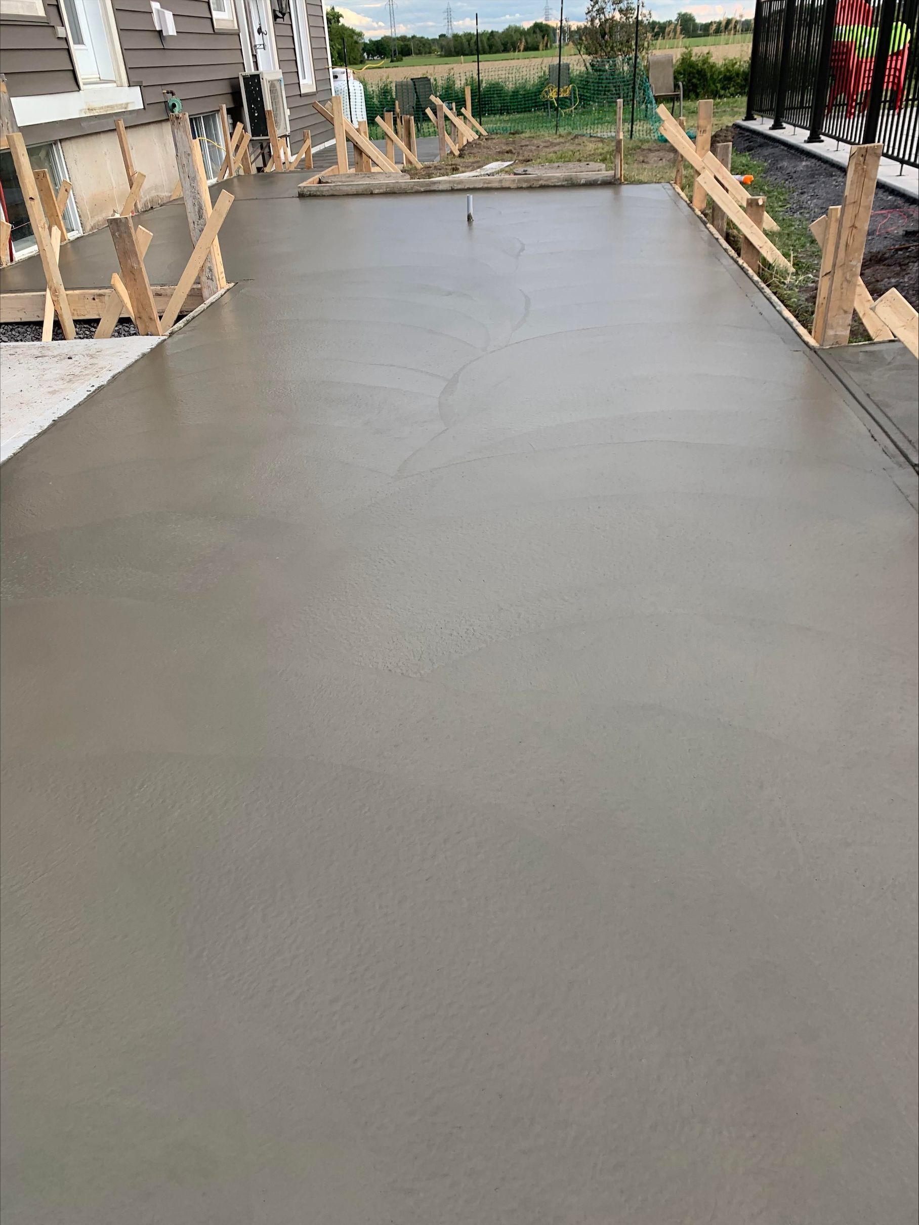 Une allée en béton est en cours de construction devant une maison.