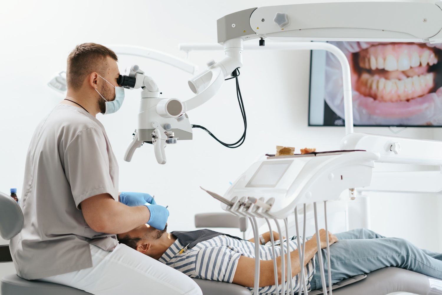 A dentist is examining a patient 's teeth with a microscope.