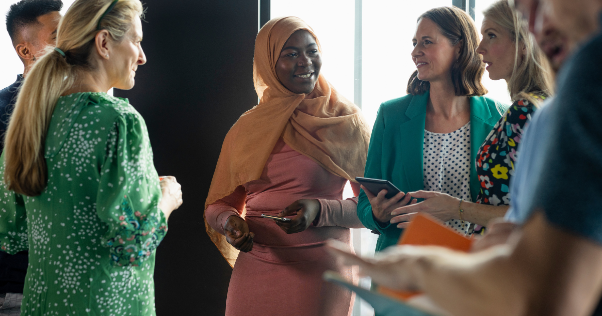 Group of people in business attire engaged in conversation, indoors.