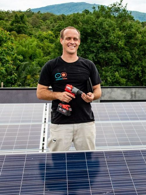 Eyekandi Solar owner standing in front of a solar panel holding a drill.