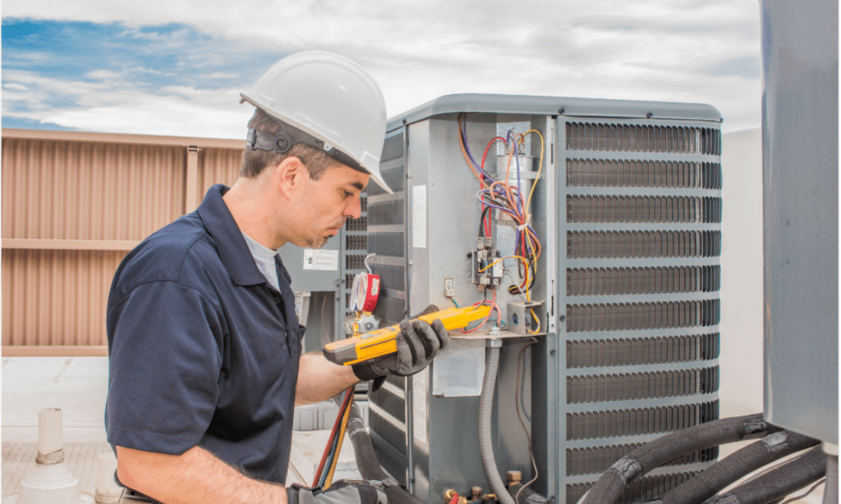 A man wearing a hard hat is working on an air conditioner.