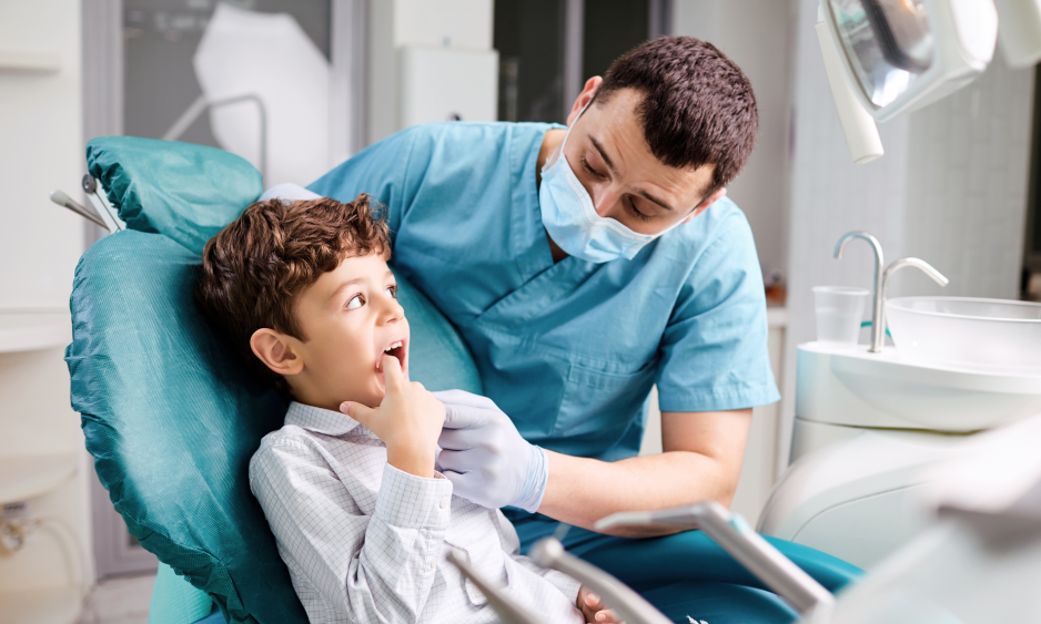 A young boy is sitting in a dental chair talking to a dentist.