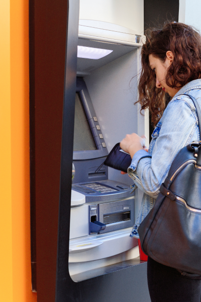 A woman is taking money out of an atm machine