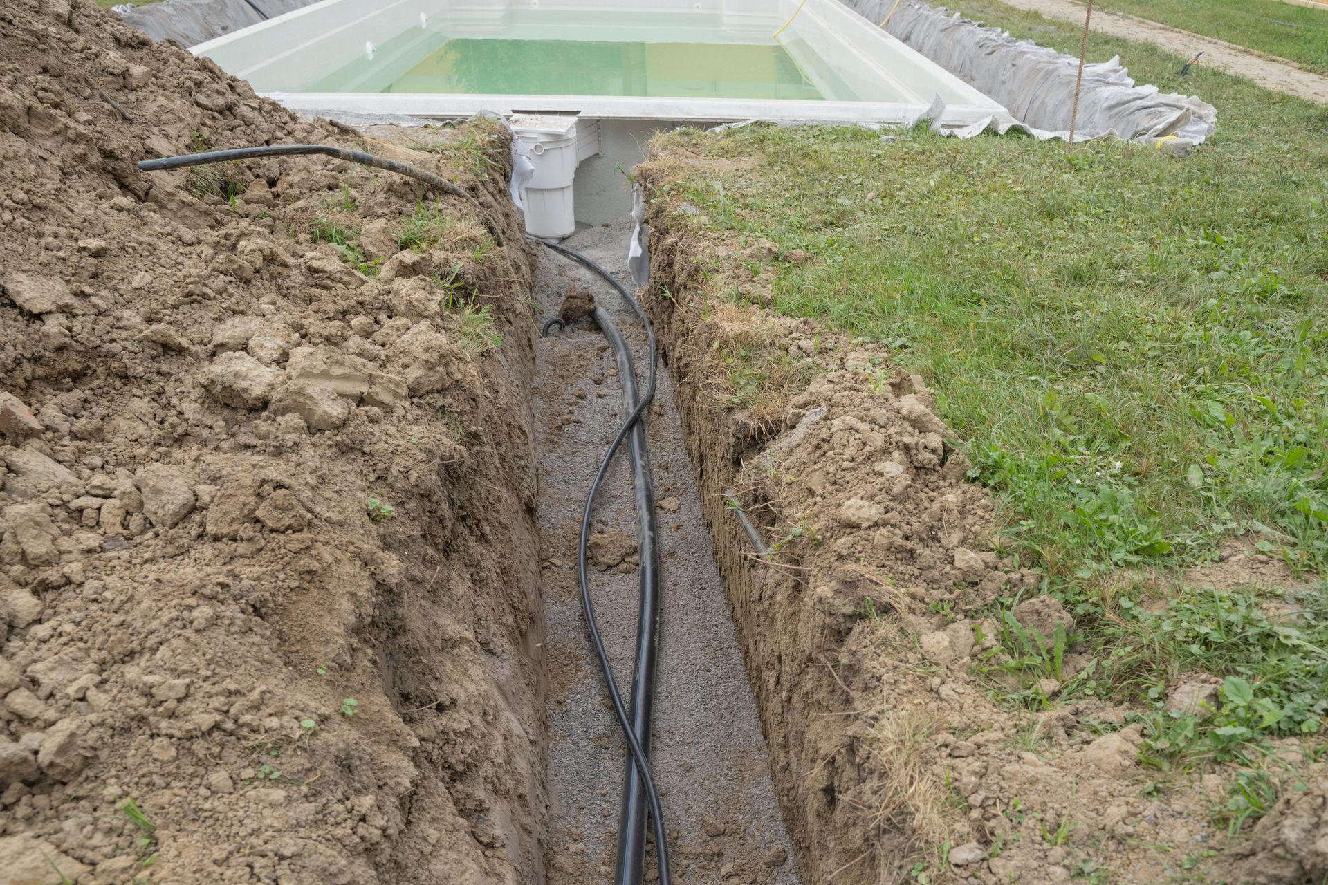 A swimming pool is being built in a trench in the ground.