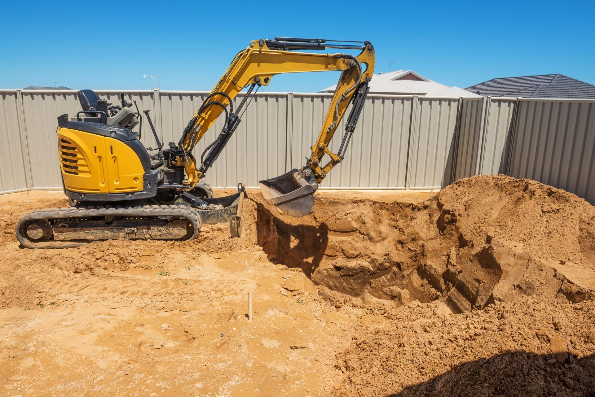 A yellow excavator is digging a hole in the ground.