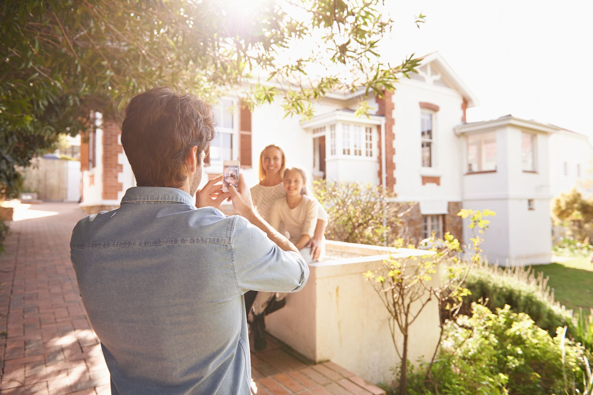 a man is taking a picture of a family in front of a house .