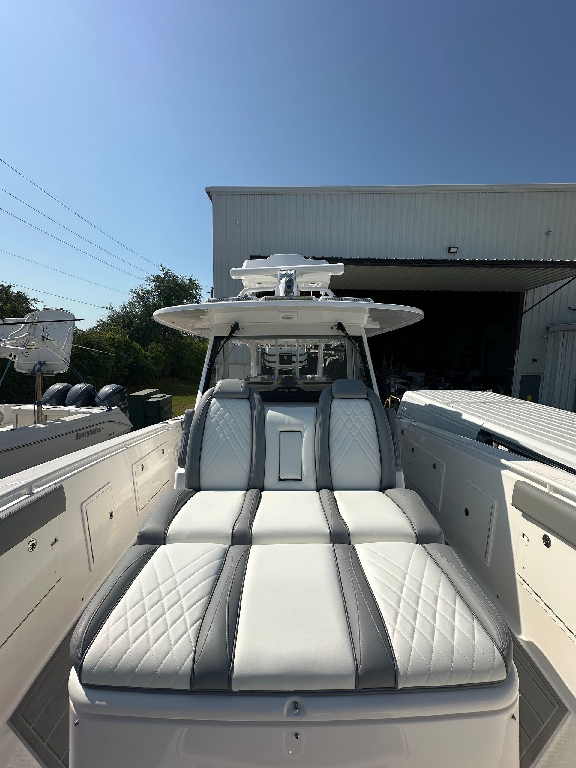 A white boat with gray seats is parked in front of a building.