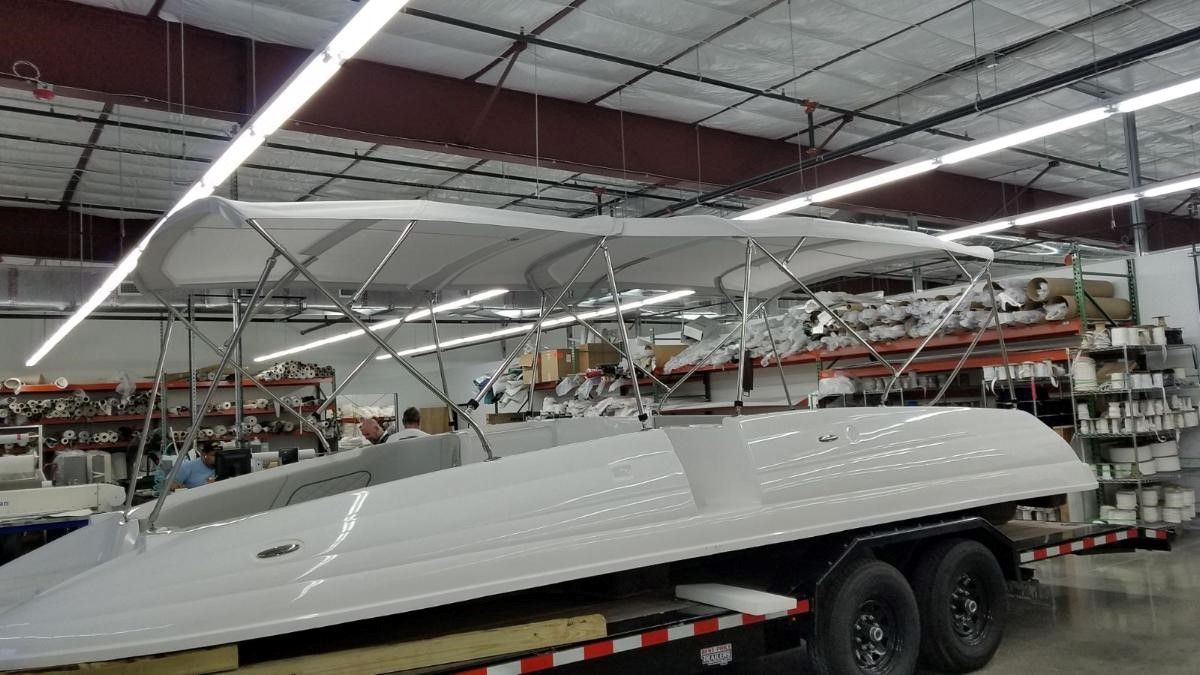 A white boat is sitting on a trailer in a warehouse.