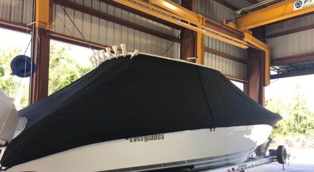 A boat is sitting in a garage with a black cover on it.