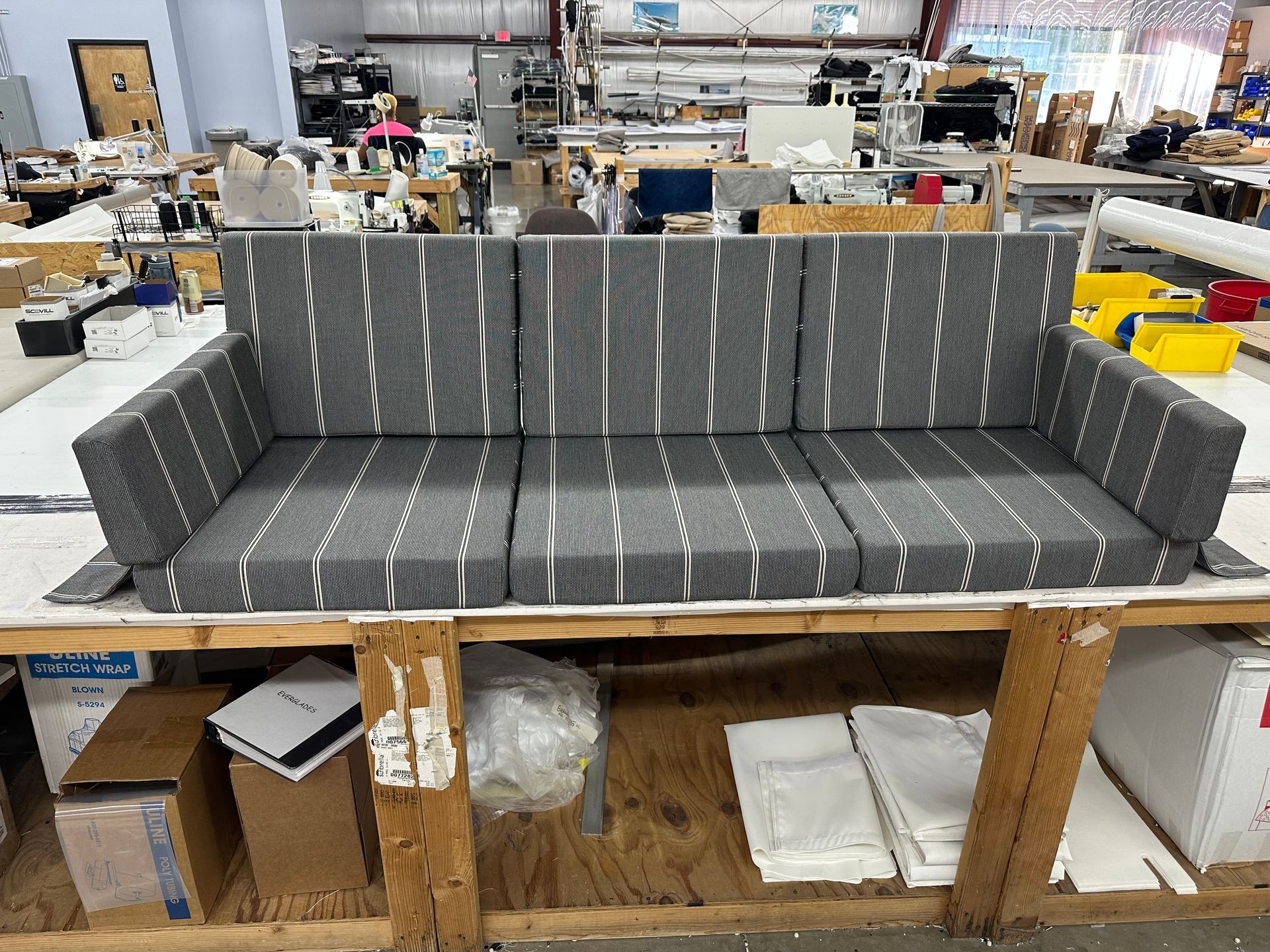 A couch is sitting on top of a wooden table in a warehouse.