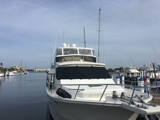 A large white boat is docked in a marina.