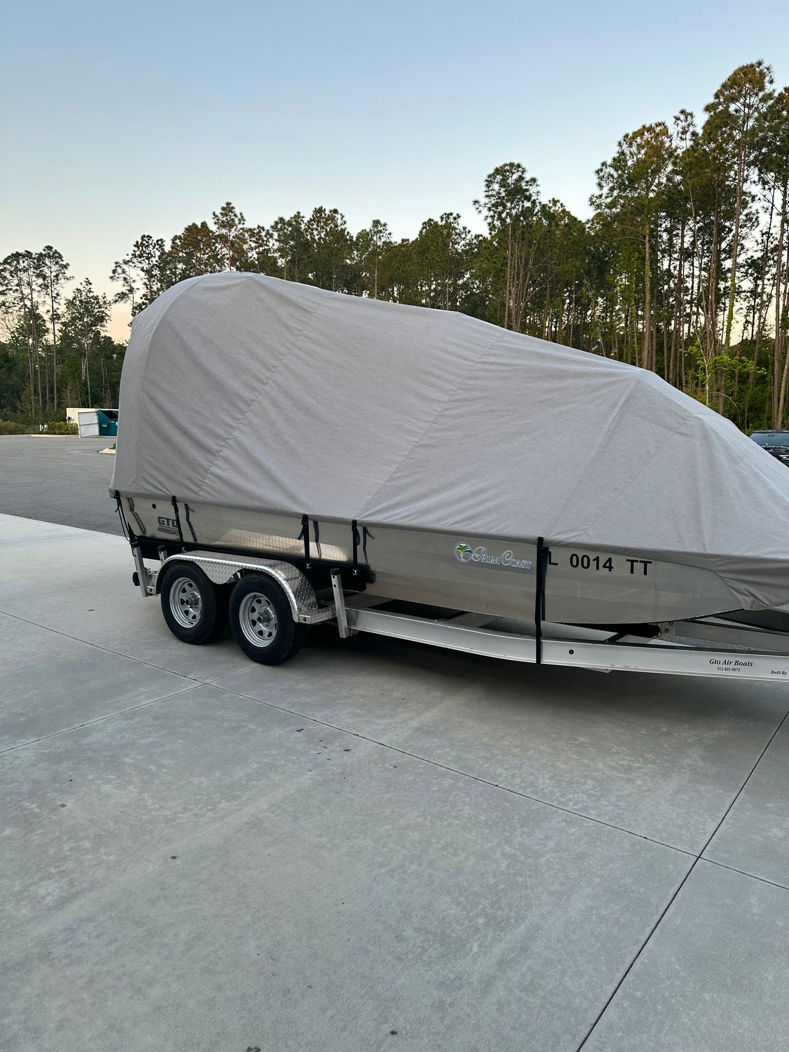 A boat with a cover on it is parked in a parking lot.